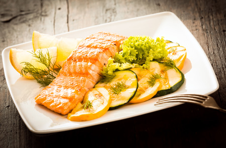Gourmet portion of grilled fresh pink salmon served with roast vegetables, lettuce and a slice of fresh lemonの写真素材