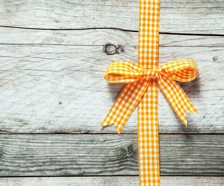 Colorful orange and white festive rustic ribbon and bow decorating a background of old cracked weathered wooden boards with copyspace for your seasonal Christmas or birthday messageの写真素材
