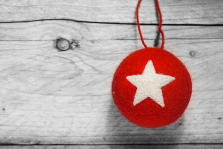 Red Christmas bauble decorated with a white star hanging on a rustic wood background with copyspace for your greeting or messageの写真素材