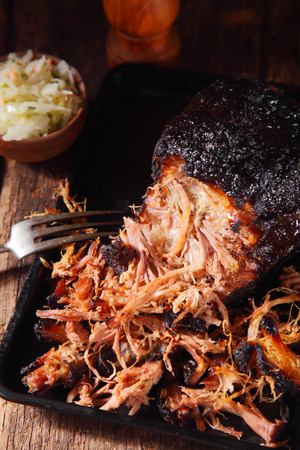 Close up Tender Pulled Pork on Black Tray, Served at Wooden Table for Lunch or Dinner.の写真素材