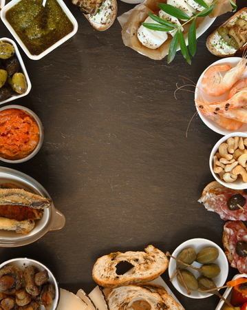 Conceptual Assorted Tasty Tapas on Brown Table with Copy Space at Centerの写真素材