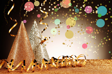 Close up Glittery Carnival Cone Hats and Gold Streamers with Confetti Effect on Glittery Table in...