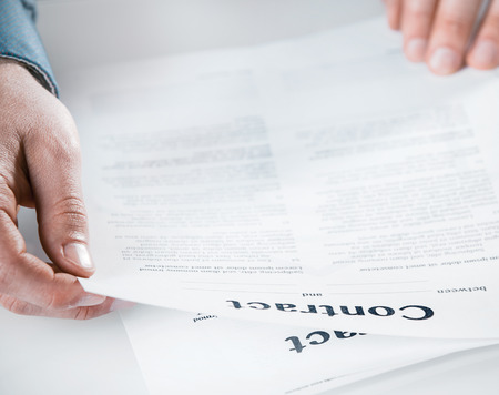 Businessman reading through a legal contract at the office before signing to close the agreement,...