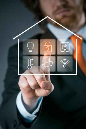Businessman using a smart house control panel activating the security setting on a transparent virtual interface Businessman using a smart house control panel activating the security setting on a transparent virtual interface
