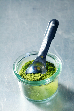 Jar of matcha powder, or Japanese powdered green tea used in tea ceremonies and as a flavoring in drinksの写真素材