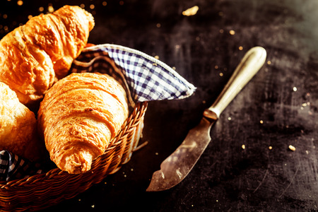 Close up Freshly Baked Buttery Croissant Bread on a Basket and a Cutting Knife on Top of the Tableの写真素材