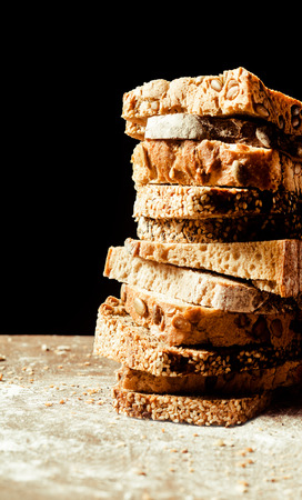 Stacked pile of assorted slices of bread with wholegrain, rye, white and seed bread on a wooden...