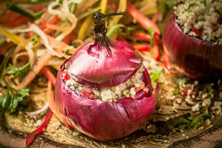 High Angle View of Healthy Vegetarian Couscous Stuffed Red Onion Served on Decorative Platter with Fresh Saladの写真素材