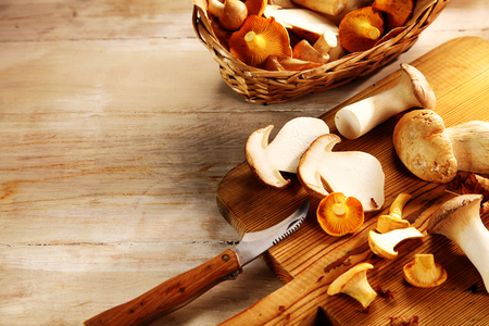 Preparing king oyster mushrooms for use as a cooking ingredient on a wooden chopping board with copyspace and a fresh mushroom border, high angle close upの写真素材