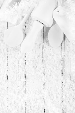 Monochromatic seasonal Christmas white cooking or baking concept with pure white wooden utensils decorated with white tinsel on a white wooden table with winter snow and copyspace, overhead viewの写真素材
