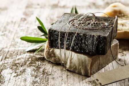 Two bars of healthy aromatic soap made with plant extracts and essential oils for a relaxing spa treatment or bath time tied with string on a rustic wood backgroundの写真素材