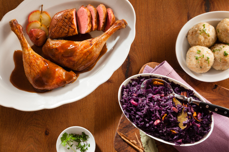 High angle view of german tradition food. Chicken drumsticks, red cabbage and traditional dumplings in overhead view on a brown wooden backgroundの写真素材