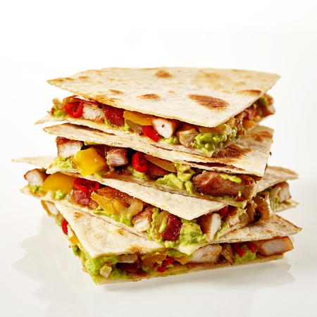 Four tex-mex turkey quesadillas filled with guacamole, tomato and peppers in a stack over white backgroundの写真素材