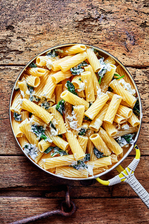 Ricotta Italian noodles or pasta recipe with spinach and grated parmesan cheese served in a pan as a healthy appetizer, overhead view on a rustic tableの写真素材