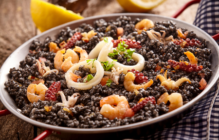 Close up of delicious steel bowl full arroz negro, fried shrimp and onion ringsの写真素材