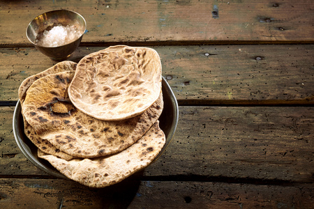 Top down first person perspective view on chapati bread beside cup and copy space on wooden tableの写真素材