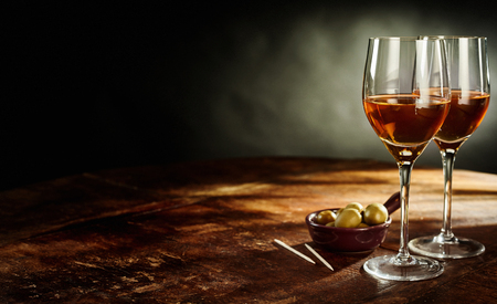Profile Still Life of Two Glasses of Warm Sherry Wine on Rustic Wooden Table with Green Olives Appetizers with Copy Spaceの写真素材