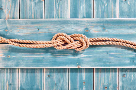 Nautical Themed Background - High Angle Still Life of Double Figure Eight Knot in Natural Rope Across Blue Painted Wood Plank Background with Copy Spaceの写真素材