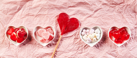Ceramic bowls in a row filled with gum drops and other tasty treats besides heart shaped lollipopの写真素材