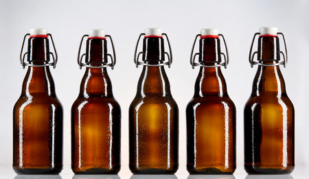 Straight on view of five blank glass bottles of beer for Oktoberfest or other concept regarding...