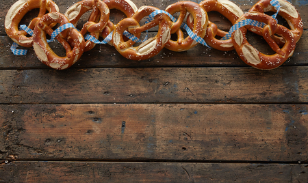 Border of traditional German pretzels on dark aged wood background with copy space for your Oktoberfest themed textの写真素材