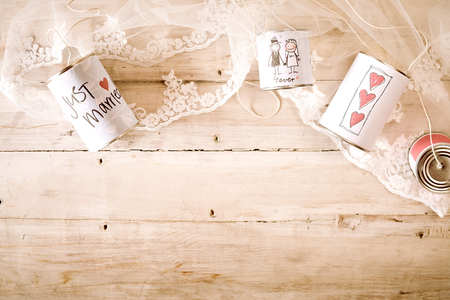 Lace and just married symbols on metal cans attached with string over wooden background. Includes copy space.の写真素材