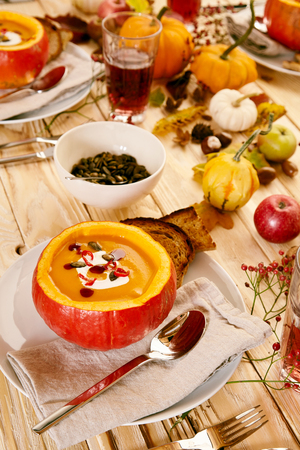 Close up on delicious pumpkin soup inside gourd with rye bread and pumpkin seedsの写真素材