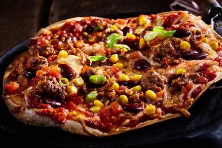 Delicious traditional Tex-Mex tortilla pizza topped with corn, beans, kidney , tomato and cheese for a nutritious fast food snackの写真素材