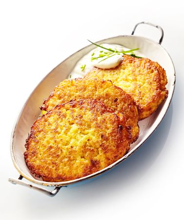 High Angle Still Life of Golden Crisp Fried Potato Rosti Pancakes Served in Dish with Creamy Dill Sauce on White Backgroundの写真素材