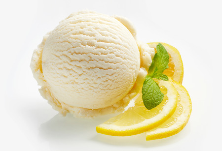 Tangy fresh lemon citrus sorbet or ice cream with sliced fresh fruit garnished with mint alongside over a white background