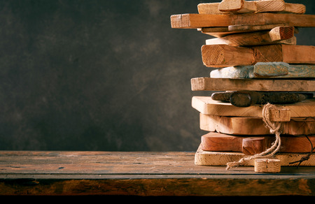 Stack of multiple old wooden chopping or cutting boards arranged to the side on a table with copy...