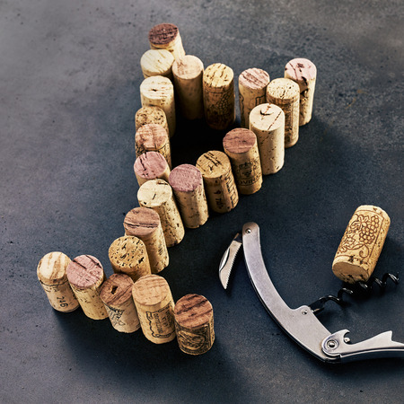 Corkscrew and shape of glass made of wine corks against dark backgroundの写真素材