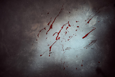 Blood splatter on a cement wall or floor at a crime scene with heavy vignetting or highlighted by a torchの写真素材