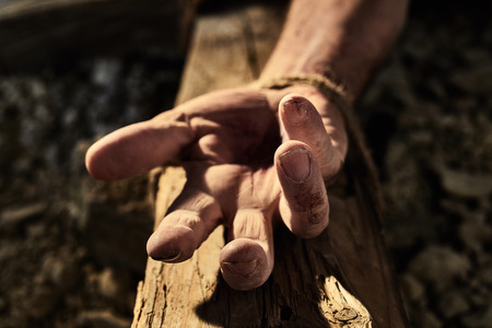 Bloodied hand with nail hole on a wooden cross conceptual of the martyrdom and crucifixion of Christ...