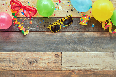 Colorful border of carnival or party accessories on a natural wood background with copy spaceの写真素材
