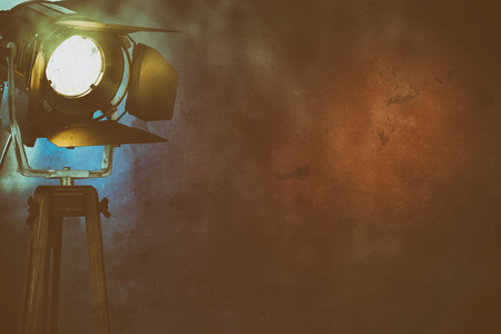 An illuminated stage light amongst dry ice smoke on a plain, dark background with copy space.