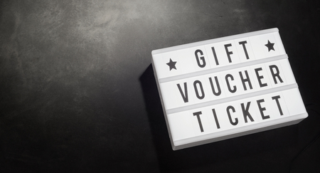 Gift voucher ticket written on a word board with stars in a cinema movie theme with a dark background and copy space.の写真素材