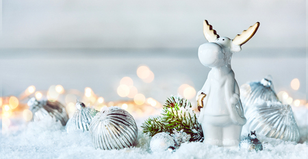 Cute little white Christmas reindeer in winter snow with silver baubles and fir foliage in a panorama banner with copy spaceの写真素材