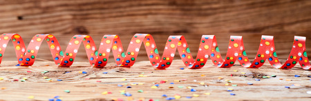 Party theme of colorful ribbon with confetti on wooden backgroundの写真素材