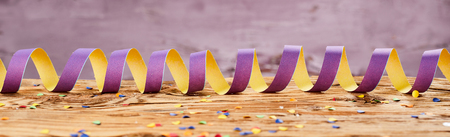 Party concept of ribbon with scattered colorful confetti on wooden surfaceの写真素材
