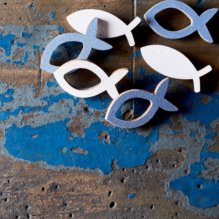 Closeup of metal Christian fish shapes on old blue and brown wood backgroundの写真素材