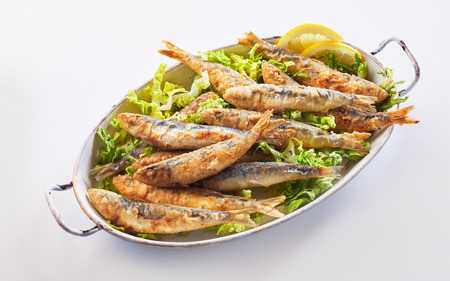 Healthy regional Greek seafood meal of crisp fried sardines in batter on fresh lettuce