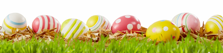 Panorama holiday banner with colorful red and yellow patterned Easter eggs on a bed of straw on the...