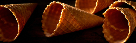 Panorama banner of empty cornets or waffle ice cream cones on a shadowy rustic wood background in a close up viewの写真素材
