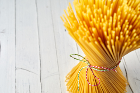 Rustic spaghetti bundled up with string and flared on high key timber background.の写真素材