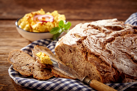 Fresh crunchy Bavarian bread with butter lying in cloth against wooden tableの写真素材