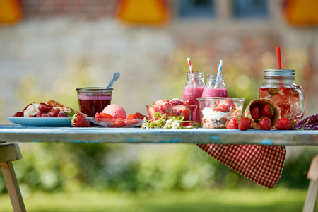 Fresh, healthy, colourful summer strawberries smoothie bowl, juices and desserts picnic on a bright outdoor table setting.の写真素材