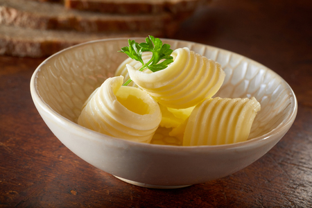 Close up Cute little bowl of fresh butter curls on wooden table for advertising, food ingredients for baking and cooking or for breakfast scenes.の写真素材