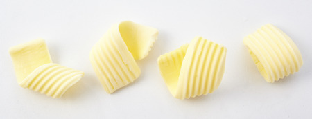 High Angle Panoramic Still Life View of Four Perfect Curls of Textured Butter on White Backgroundの写真素材