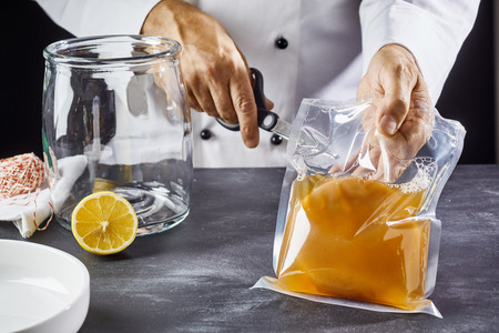 Man opening bag with symbiotic culture of bacteria and yeast to prepare kombucha teaの写真素材